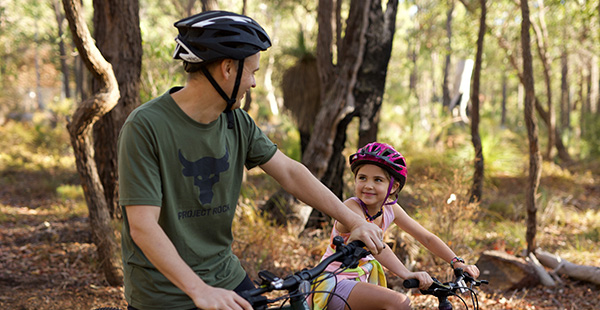 A father and daughter riding bikes in the Cardup nature reserve, right next door to Constellar